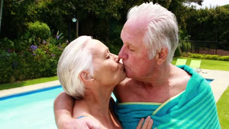 senior couple kissing each other in the poolside