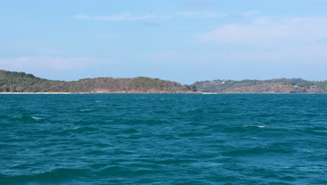 gentle waves roll under a clear sky near phuket, thailand. the tranquil scene captures the island's natural beauty and calm atmosphere