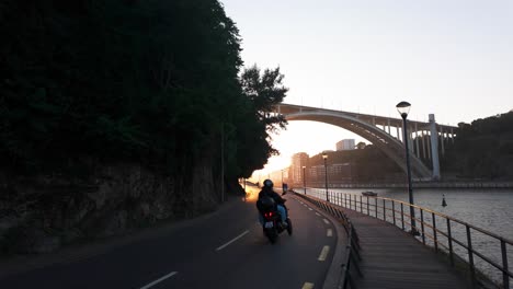 sunlit road curves alongside a rocky hillside with lush greenery in vila nova de gaia by the douro river
