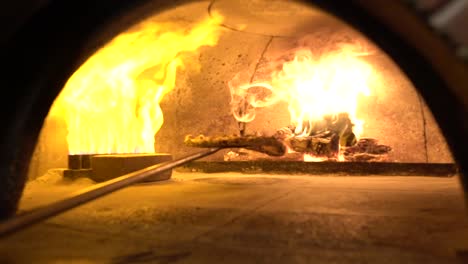 bringing pizza out of the brick oven slow motion