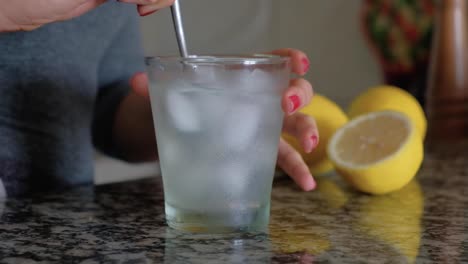 Frau-Rührt-Mit-Einem-Löffel-Ein-Glas-Mit-Limonade-Und-Eiswürfeln