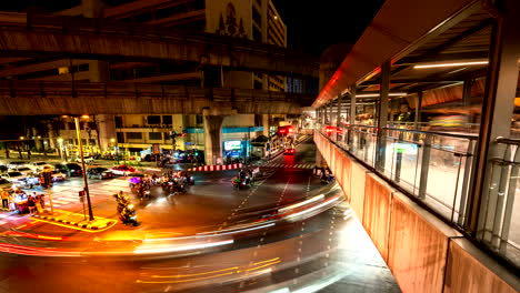 dynamic nightlapse at busy traffic intersection and pedestrian bridge, bangkok
