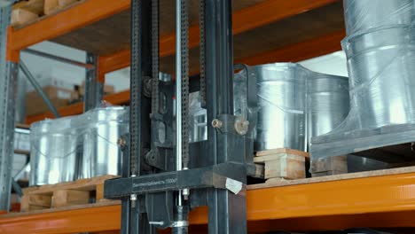 electric forklift with metal guides lifts a pallet of goods from a shelf in an industrial warehouse. storage of packages with metal containers