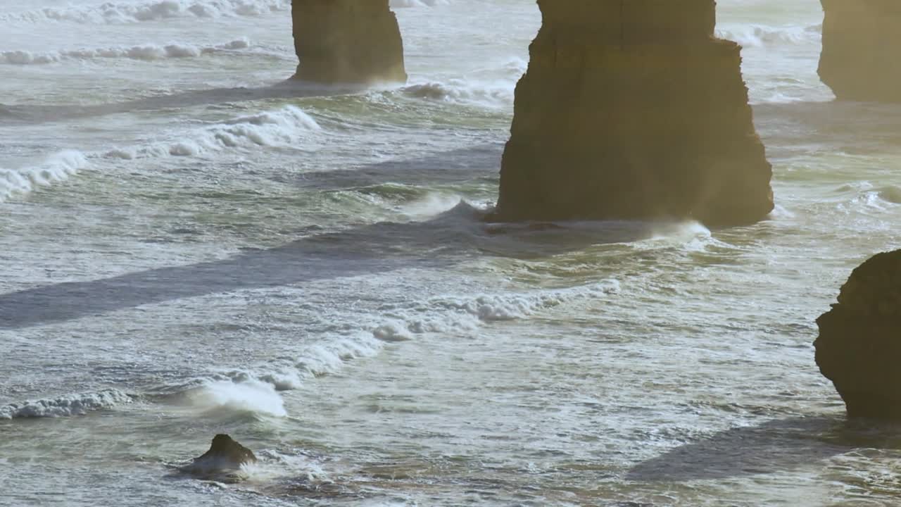 Close-up view of ocean waves hitting towering rock formations, highlighting dynamic sea movement and natural erosion.
