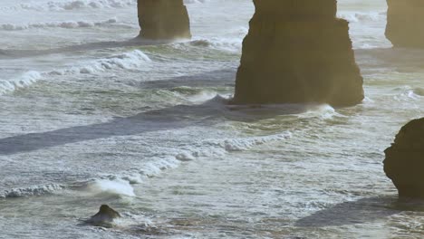 close-up view of ocean waves hitting towering rock formations, highlighting dynamic sea movement and natural erosion.