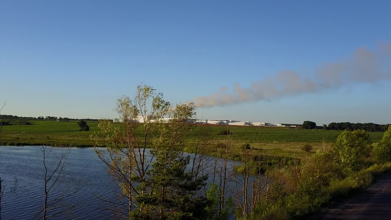 Factory In The Middle Farmland. Factory pipes polluting air on a green field