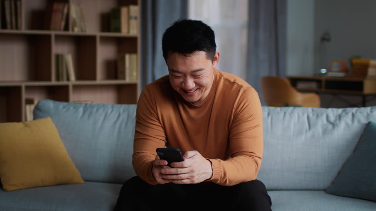 소파에서 스마트폰을 사용하는 남자