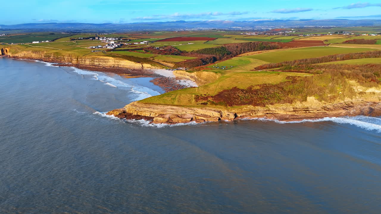 Vista aerea panoramica del villaggio di Southerndown e della Heritage Coast. Prospettiva elevata della costa, dei campi verdi e degli insediamenti distanti nella Vale of Glamorgan, Galles.