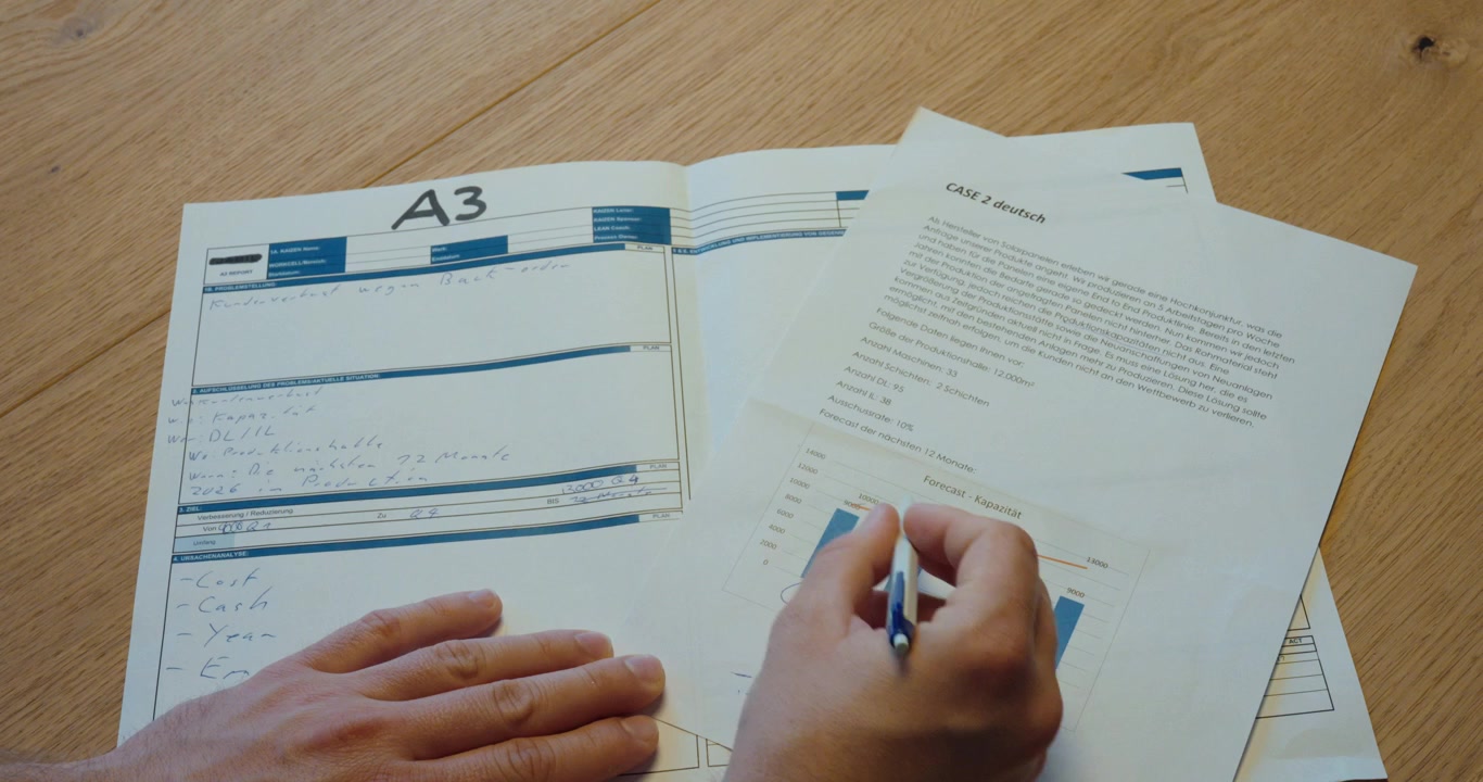 Person writing on an A3 report sheet, representing structured problem solving, root cause analysis, and continuous improvement.