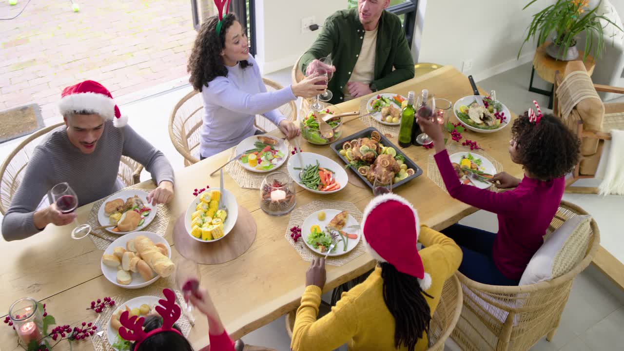 Diverse friends gathering in dining room serving roast, uncorking bottle, pouring wine and toasting