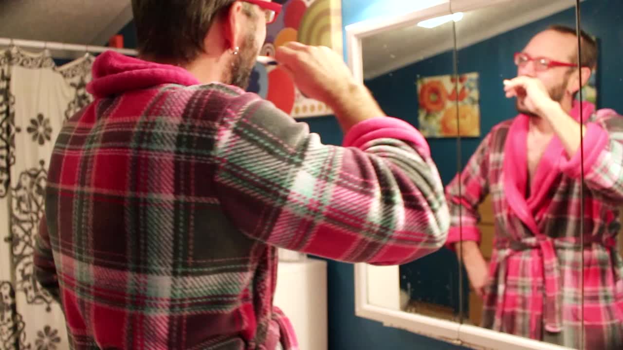 Man brushing his teeth in the bathroom mirror.