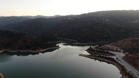 Top-view-of-Steven's-Creek-Reservoir-Lakeshore,-with-a-road-and-cars-on-the-right-side-at-Cupertino,-California