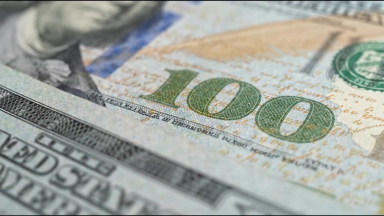 Bank teller calculating stack of us dollar bills in modern office