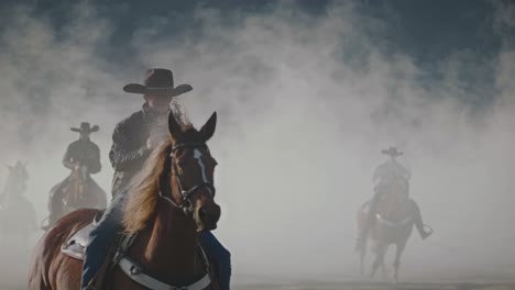 cowboys riding horses in a misty landscape