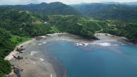 Impresionante-Vista-Aérea-De-La-Colorida-Cala-De-La-Isla-Con-Exuberante-Vegetación-Y-Olas-Del-Océano