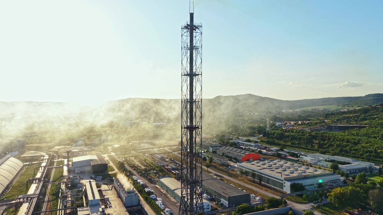 Area industriale con grande torre ed edifici sotto un cielo azzurro e limpido nel tardo pomeriggio in una zona industriale