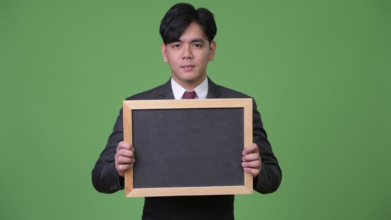 젊은 잘생긴 아시아 사업가 블랙보드를 보여줍니다.