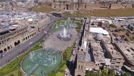 an aerial shot of the city of erbil showing the ancient erbil citadel and the garden opposite the castle with water fountains and the popular market