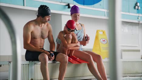 A Relaxing Moment by the Poolside: A Coach and Young Swimmers Prepare for Training with Strength and Focus in a Swimming Facility Environment