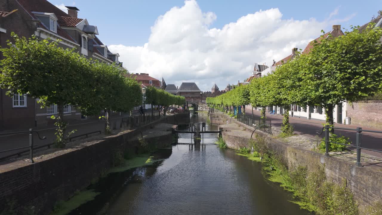 Tilt up to historic Koppelpoort gate over canal with scenic water reflection and old architecture, Amersfoort