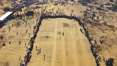 aerial drone shot of a crowd of hundreds of people at a village event