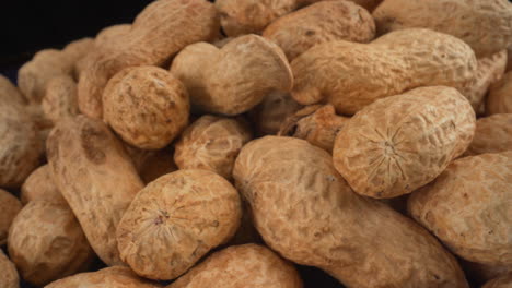 peanuts in shells macro moving, food product used in many recipes like chocolates, sauces and oils, known allergen, healthy nuts, peanut allergy, 4k shot