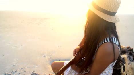 chica india en sunhat sentada tocando la guitarra