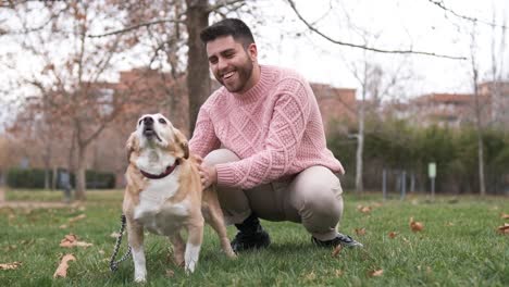 man petting his dog while enjoying a day together outdoors in the park.