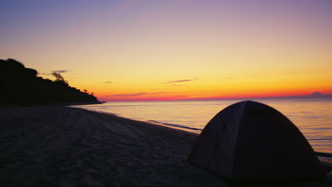 Tienda-De-Campaña-En-La-Playa-De-Arena-Oscura-En-La-Mañana-Dorada-Del-Amanecer.-Camping-Océano-Costa