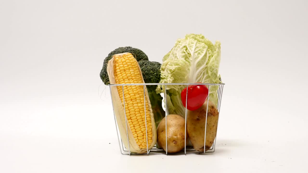 verduras frescas en una canasta sobre un fondo blanco. stop motion animation loop