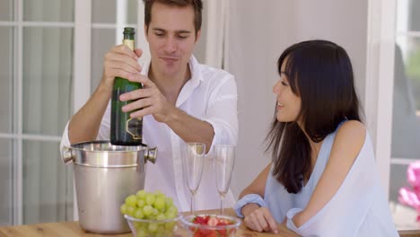 smiling young couple pouring champagne to drink