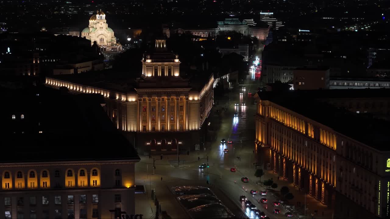 Night drone capture of Sofia’s city center featuring the Bulgarian National Assembly, the illuminated Alexander Nevsky Cathedral, and surrounding glowing buildings