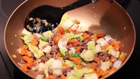 agitar y cocinar verduras mezcladas con carne en una sartén