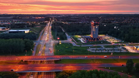 sunset view of city skyline and highway. a vibrant sunset casts colors over a busy highway and a modern hotel in an urban landscape