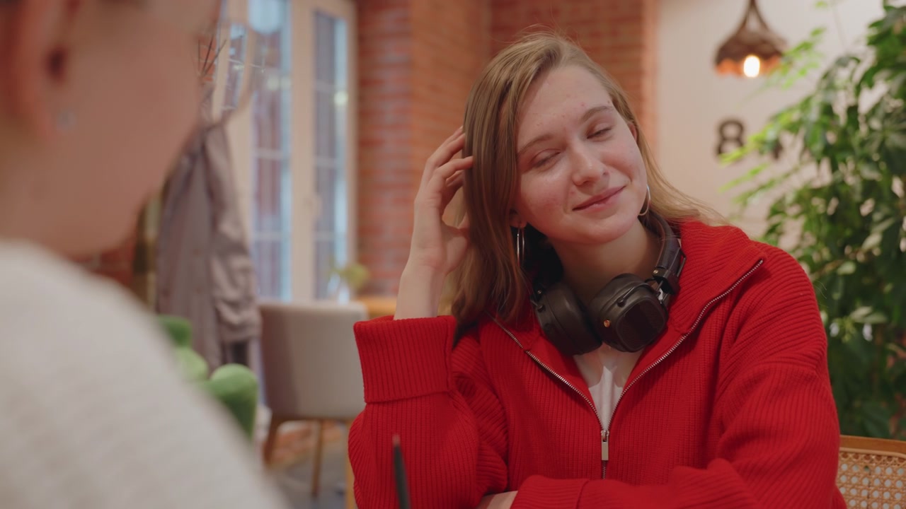 Jonge vrouw lacht en luistert naar een vriendin in een café