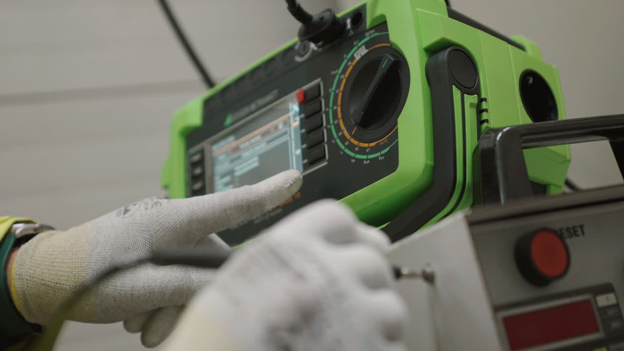 Close-up of technician adjusting green machine, safety gear visible