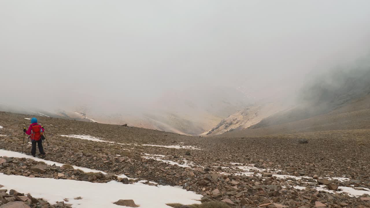 турист-рюкзачник спускается с горы, покрытой снегом, высокий атлас, марокко