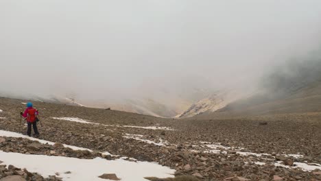 tourist backpacker descending from the snow covered mountain, high atlas, morocco