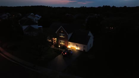 person leaving house and gets into car in american neighborhood at dusk. aerial top down shot. illuminated house in american suburb. christmas decoration in noble district of usa. virginia, usa.