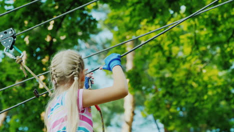 entretenimiento en el campamento de verano - un niño aprende a usar cables de seguros trepa alto en las ramas de