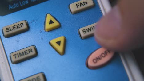 person presses buttons on air conditioner remote macro