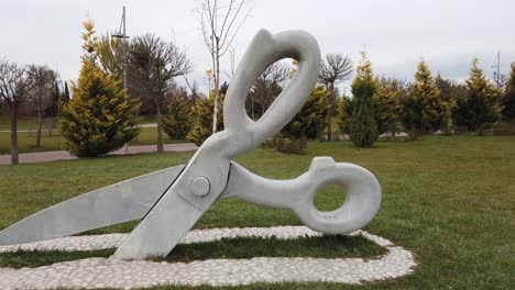 escultura de tijeras colocada sobre el césped en el parque