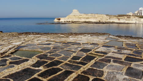 An-aerial-drone-shot-slowly-pans-across-the-rock-cut-Salt-Pans-and-beautiful-coast-of-Gozo-Island-in-Malta