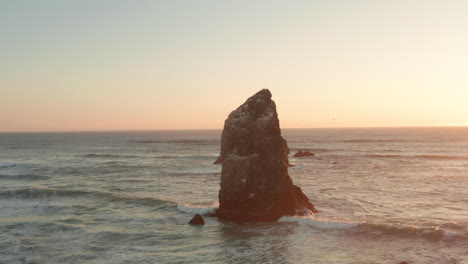 Circling-aerial-shot-of-two-large-sea-stacks-at-sunset