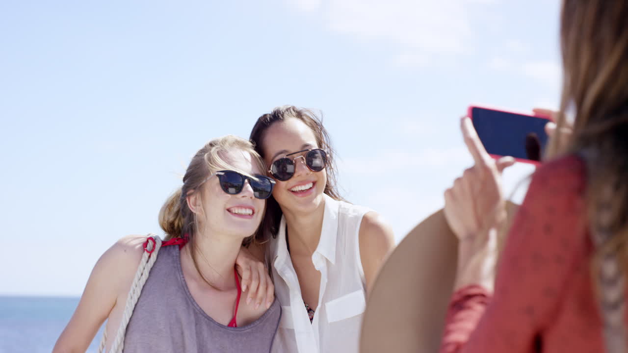 Gruppo di ragazze adolescenti che scattano una foto con il cellulare in spiaggia in vacanza estiva, primo piano