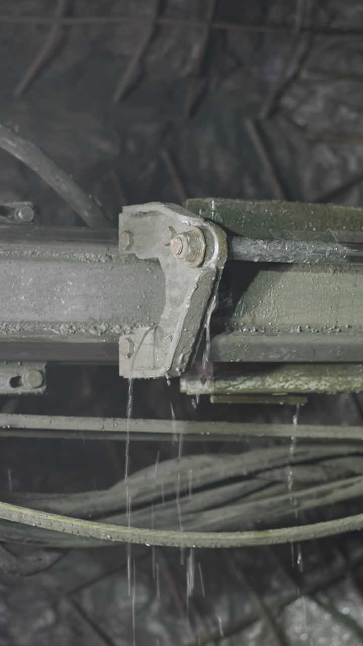 Robot drill with pipes and coolant operates in ore mine. Professional machinery equipment drills holes for setting explosives in walls closeup