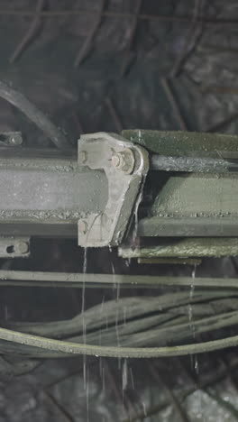 robot drill with pipes and coolant operates in ore mine. professional machinery equipment drills holes for setting explosives in walls closeup