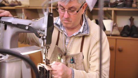 bespoke shoemaker stitching together leather pieces for shoe