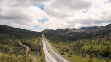 Cars-driving-down-highway-in-peaceful-green-California-mountains,-AERIAL
