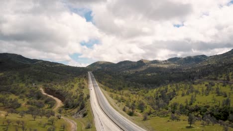 cars driving down highway in peaceful green california mountains, aerial